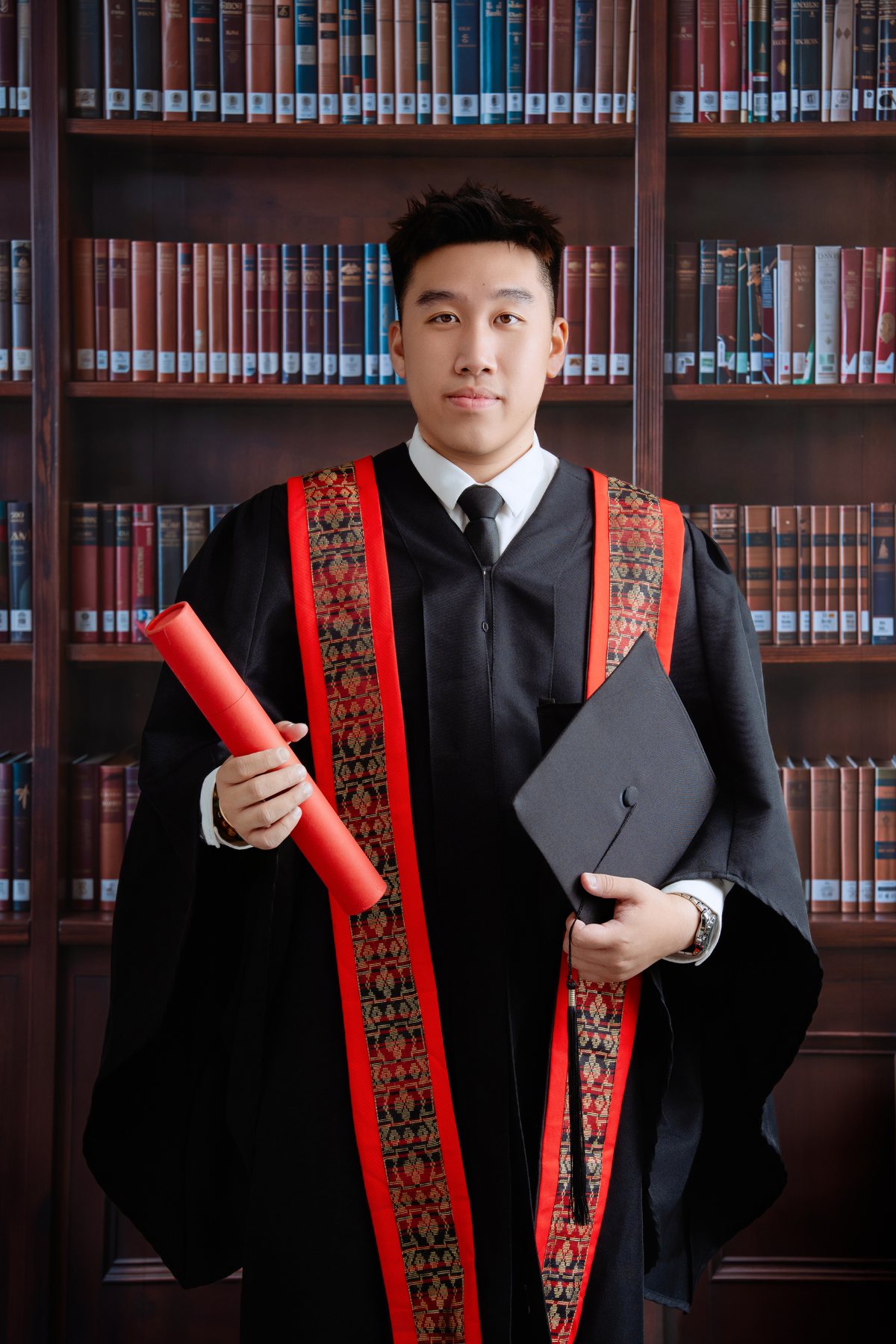 Individual graduate portrait with robe and diploma scroll